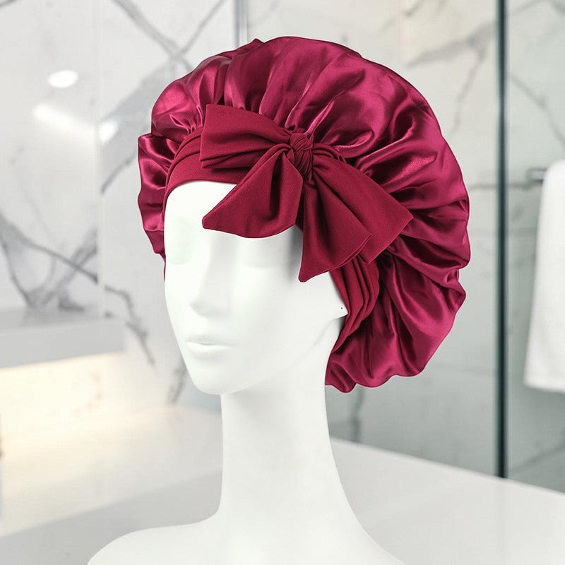 Gorro de dormir zafiropulse PERENNE Silk Slumber en color burdeos de satén con lazo decorativo sobre maniquí blanco