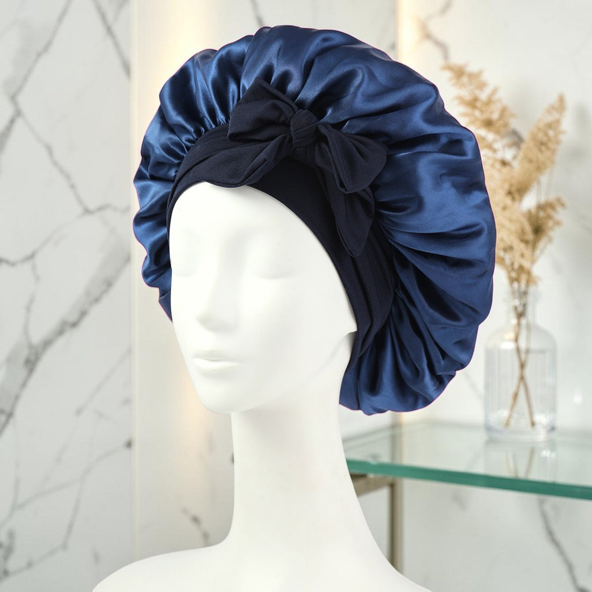 Gorro de satén azul marino PERENNE Silk Slumber de zafiropulse con lazo decorativo sobre maniquí