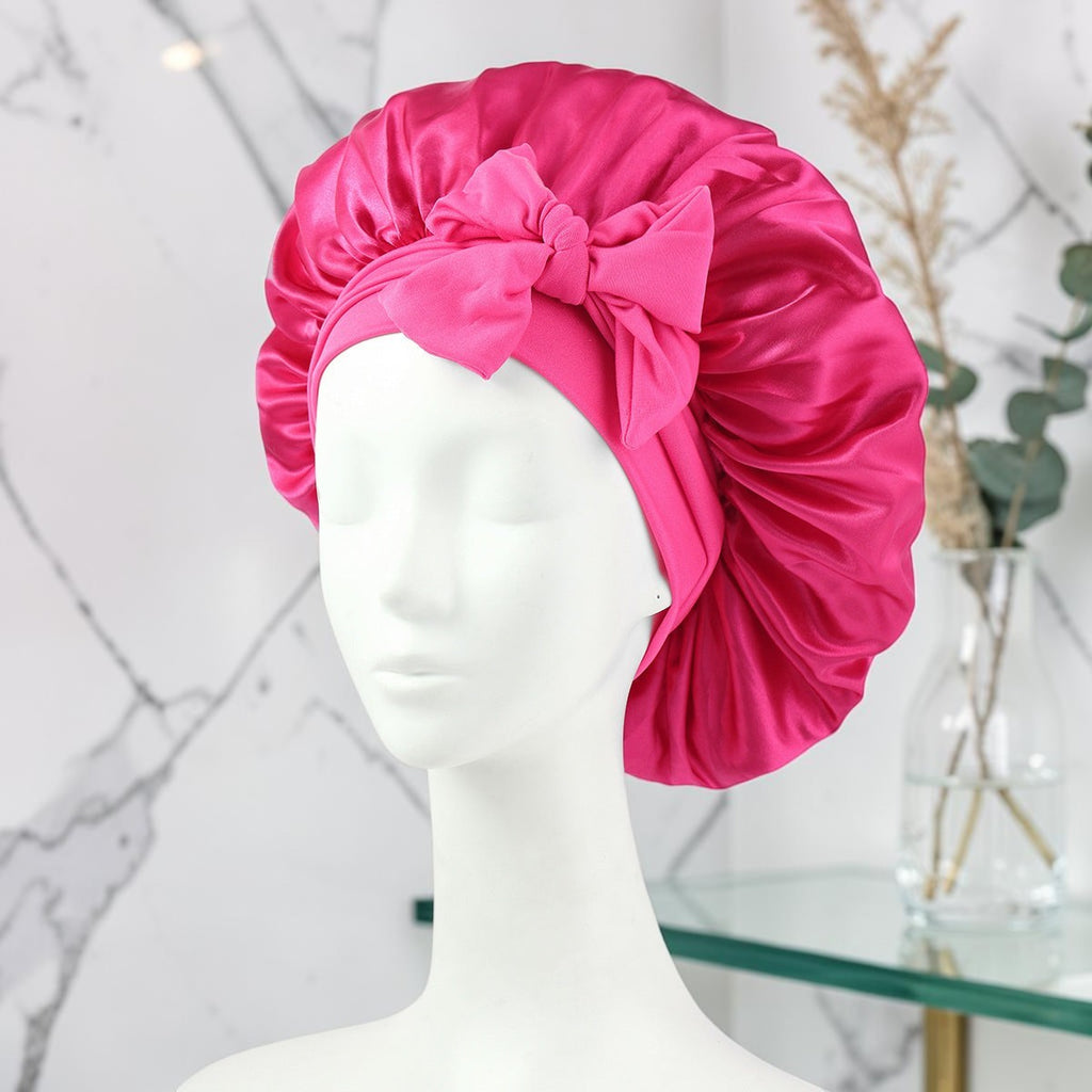 Gorro de satén fucsia PERENNE Silk Slumber de zafiropulse con lazo decorativo sobre maniquí para cuidado capilar