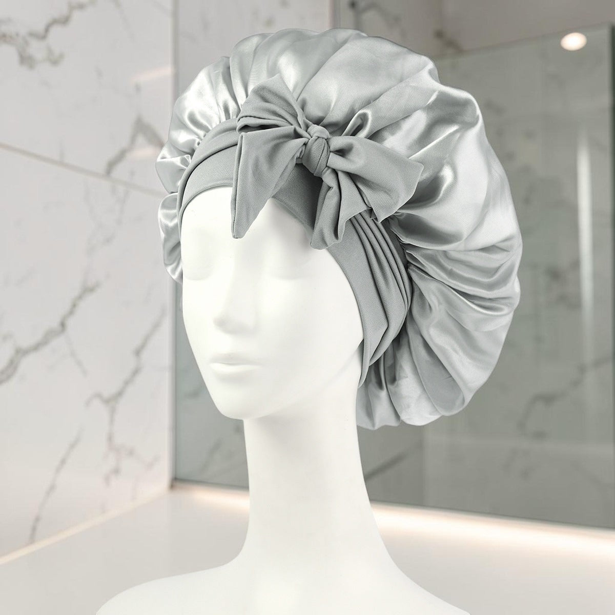 Gorro de satén gris PERENNE Silk Slumber de zafiropulse con lazo decorativo sobre maniquí para cuidado del cabello
