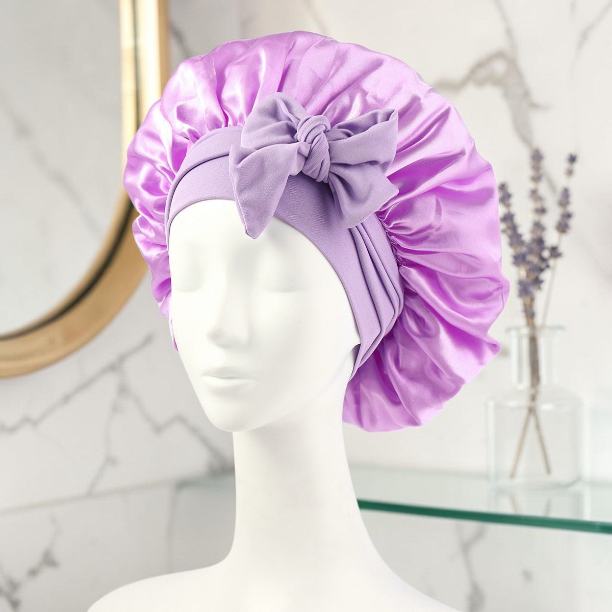 Gorro de satén lila PERENNE Silk Slumber de zafiropulse con lazo decorativo sobre maniquí para cuidado del cabello
