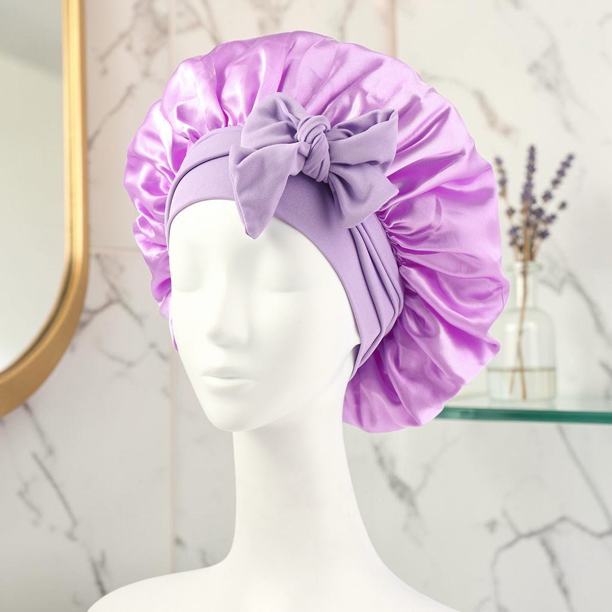 Gorro de satén lila PERENNE Silk Slumber de zafiropulse con lazo decorativo sobre maniquí para cuidado del cabello