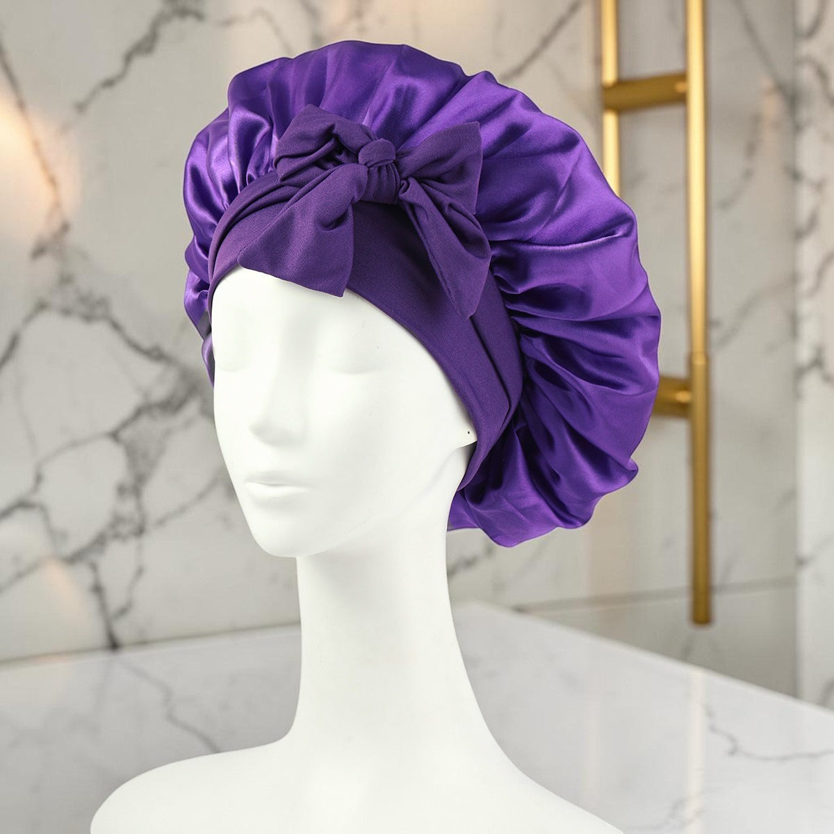 Gorro de satén morado PERENNE Silk Slumber de zafiropulse con lazo decorativo sobre maniquí para cuidado del cabello
