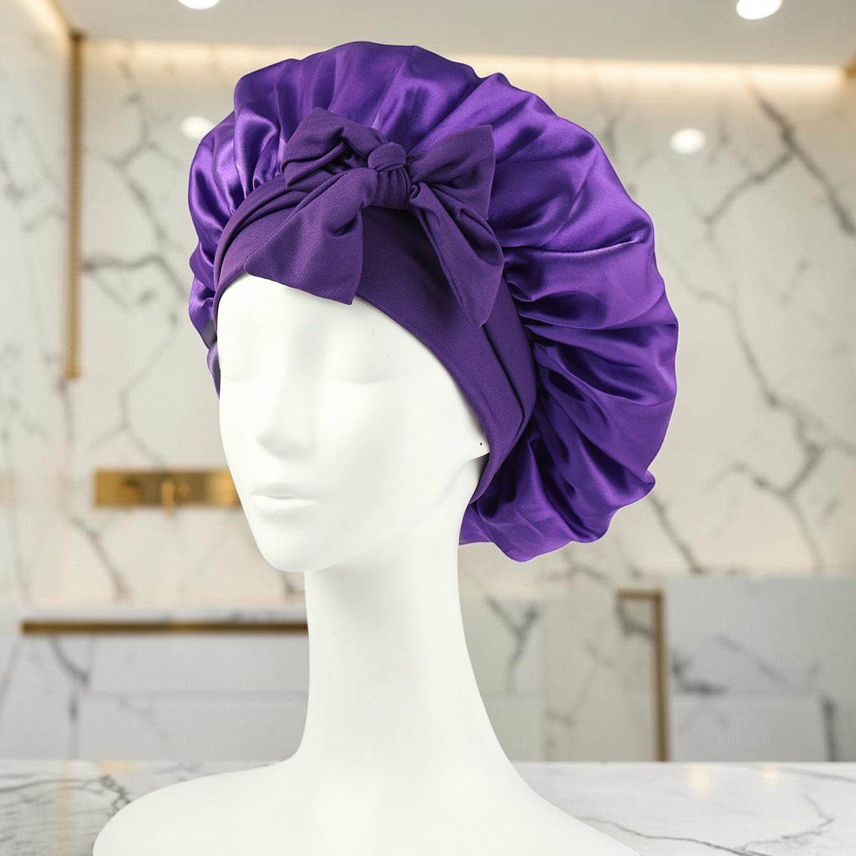 Gorro de satén morado zafiropulse PERENNE Silk Slumber con lazo decorativo sobre maniquí para cuidado del cabello