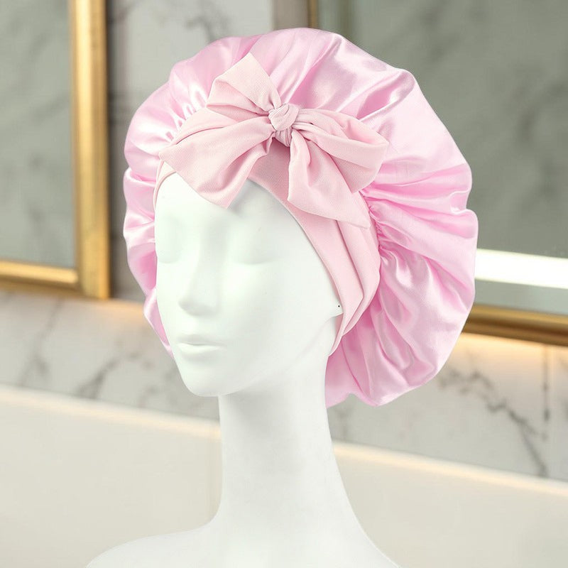 Gorro de satén rosa PERENNE Silk Slumber de zafiropulse con lazo decorativo sobre maniquí para cuidado capilar