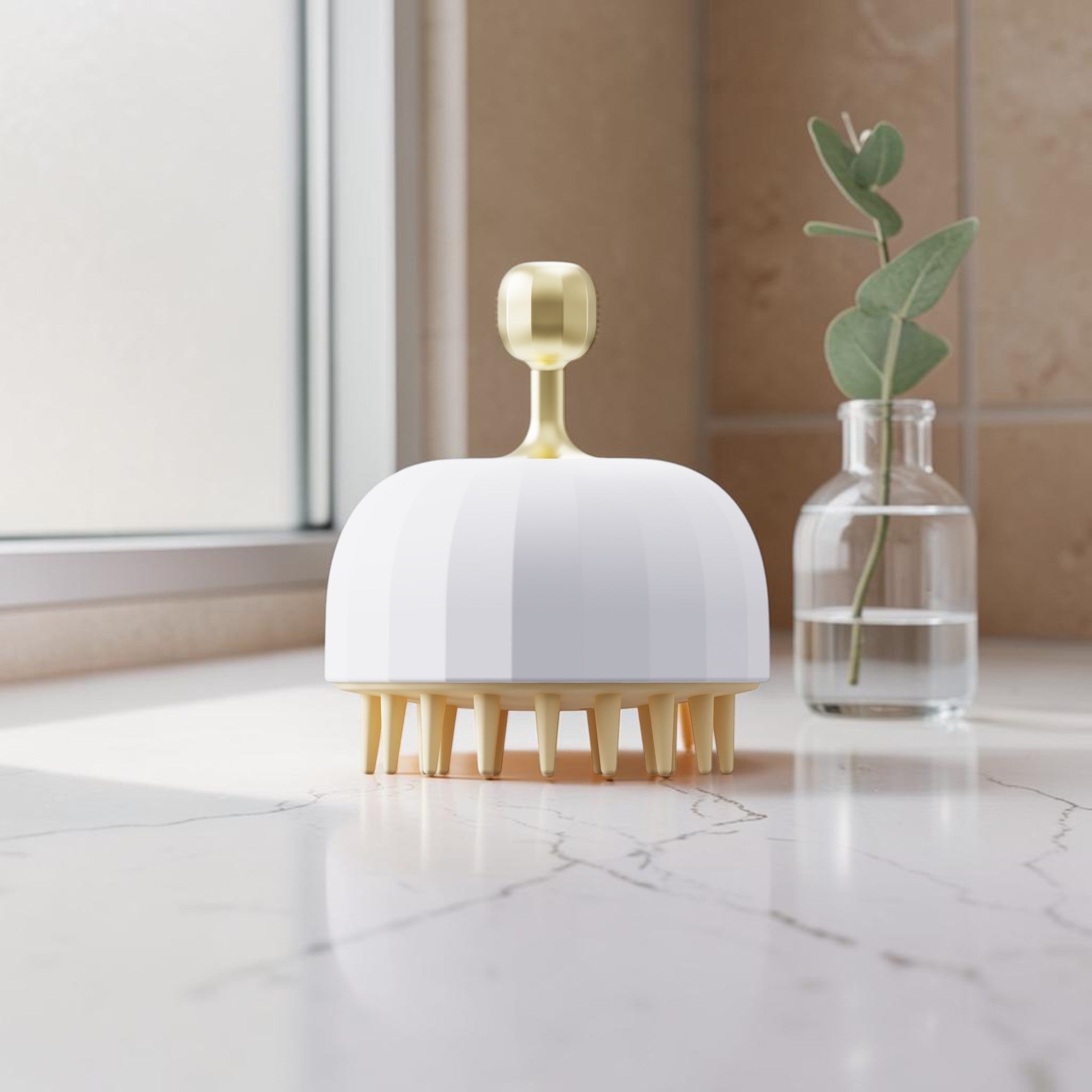 Cepillo masajeador de cuero cabelludo zafiropulse PERENNE Glow Brush en blanco y dorado sobre encimera de mármol.
